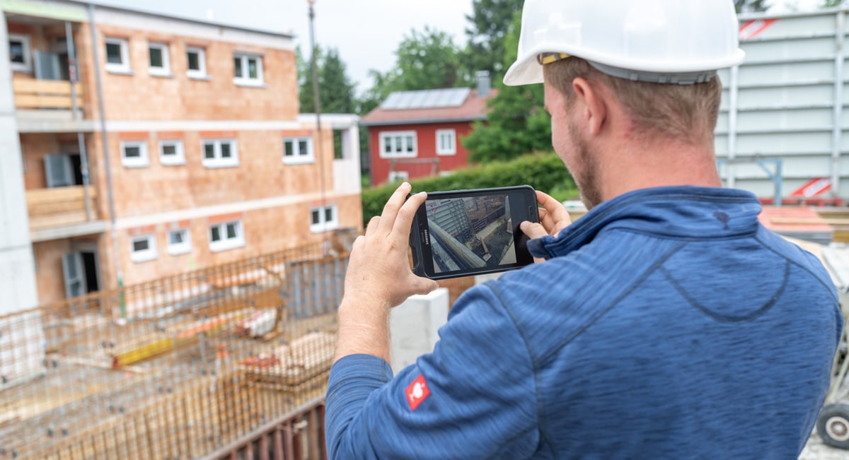 Arbeiter fotografiert mit Tablet die Baustelle